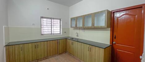 A kitchen with wooden cabinets, a sink, and a window with bars.