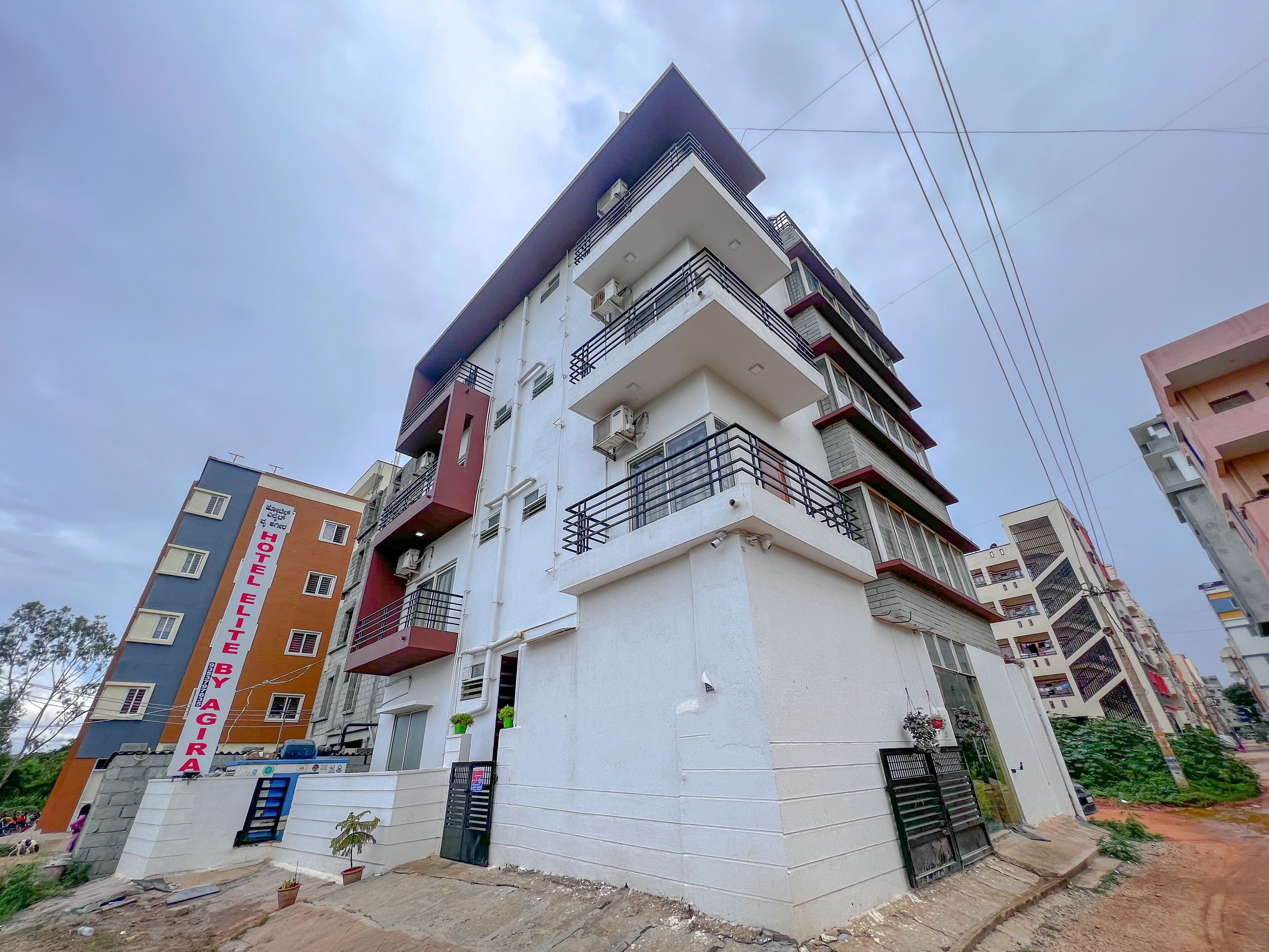 A multi-story hotel with balconies, a sign indicating it is a hotel by Agira, and a gated entrance.