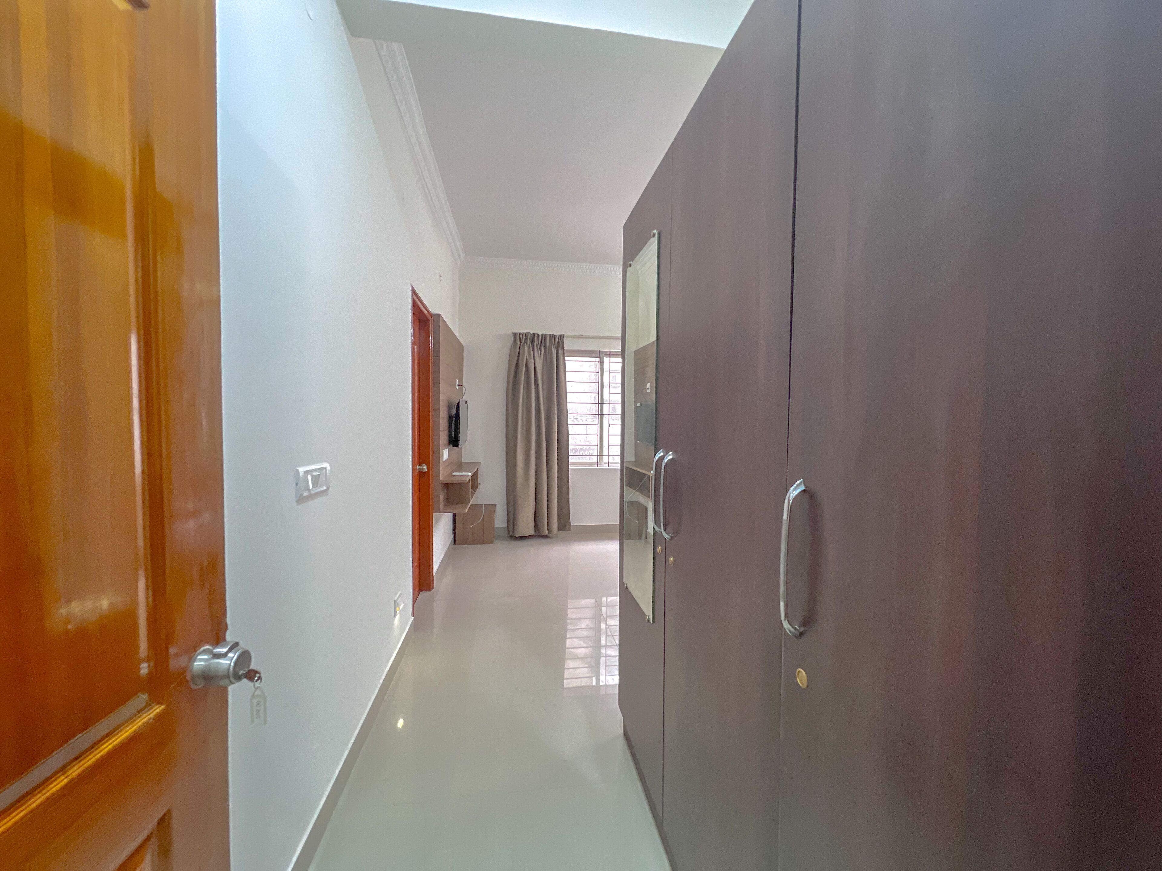 Un passadís amb una porta de fusta, un armari i una finestra amb cortines.