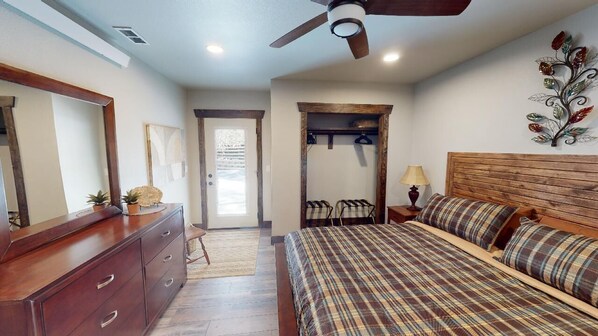 Un dormitorio con una cama de madera, ventilador de techo, cómoda y espejo.