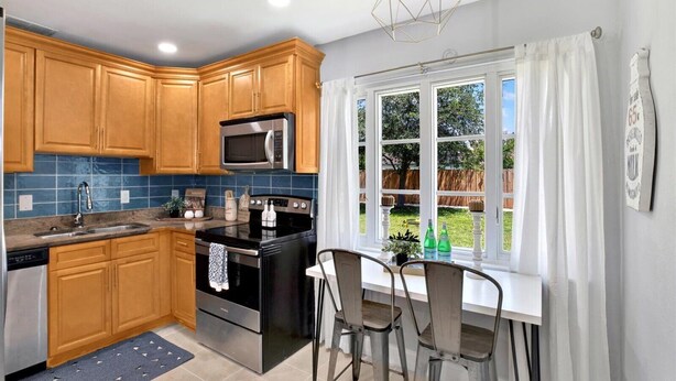 A kitchen with wooden cabinets, a microwave, an oven, and a window with a view of the backyard.