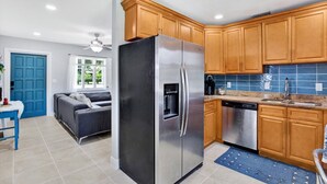 A modern kitchen with wooden cabinets, stainless steel appliances, and a blue tiled backsplash.