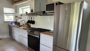 Una cocina moderna con electrodomésticos de acero inoxidable, armarios blancos y suelo de madera.