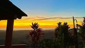 Une vue d’un coucher de soleil avec un ciel dégagé, une lune lointaine et un paysage verdoyant.