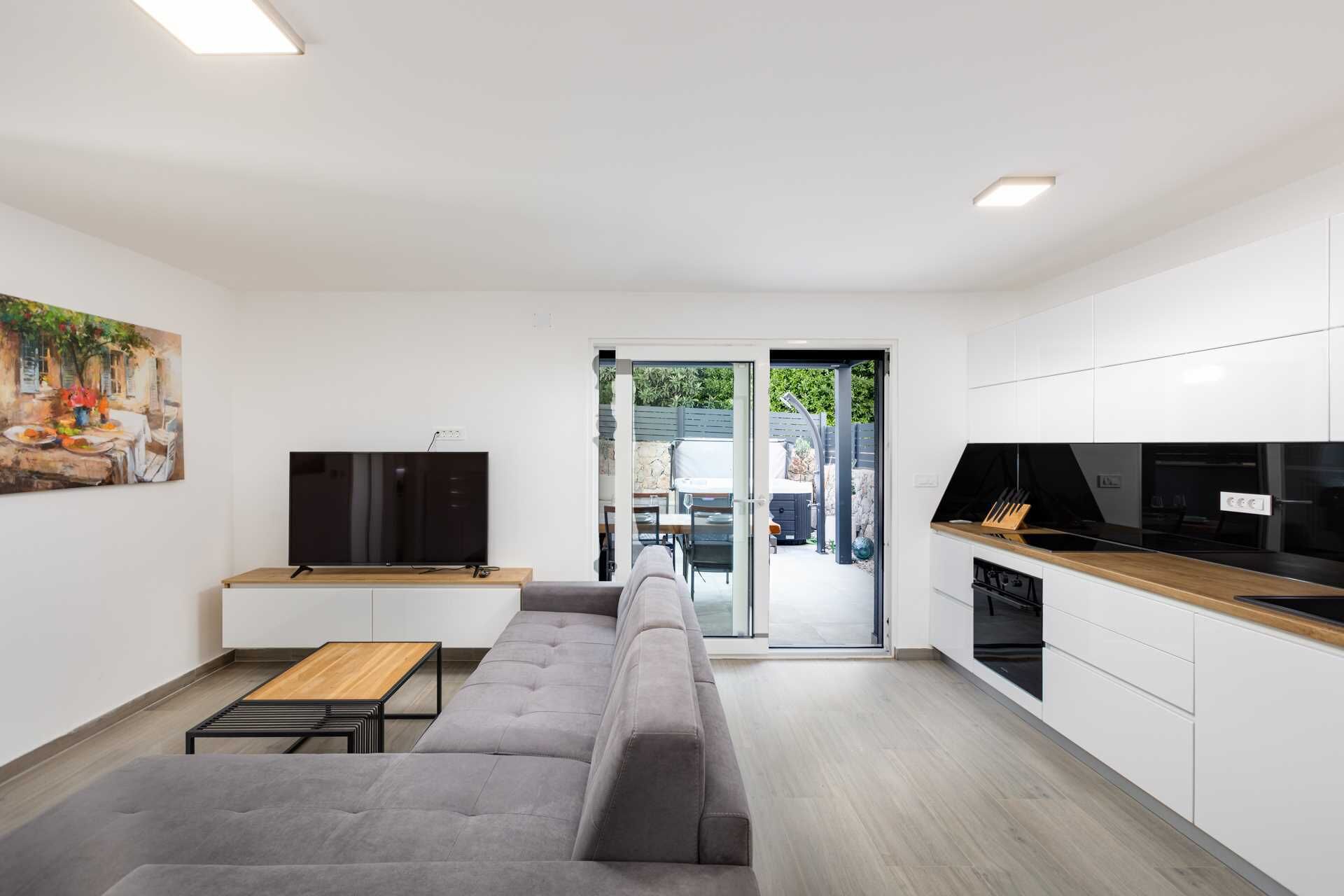 Una sala de estar moderna con un sofá gris, una mesa de centro de madera y un televisor de pantalla plana.
