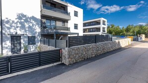 Ein modernes Mehrfamilienhaus mit Balkonen, einer Steinmauern und einem klaren Himmel.