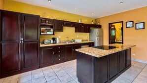 Una cocina moderna con armarios de madera oscura, encimeras de granito y una isla central.