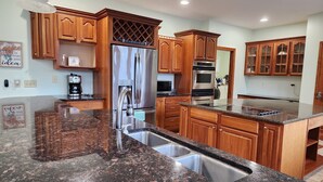 Una cocina moderna con encimeras de granito, electrodomésticos de acero inoxidable y armarios de madera.