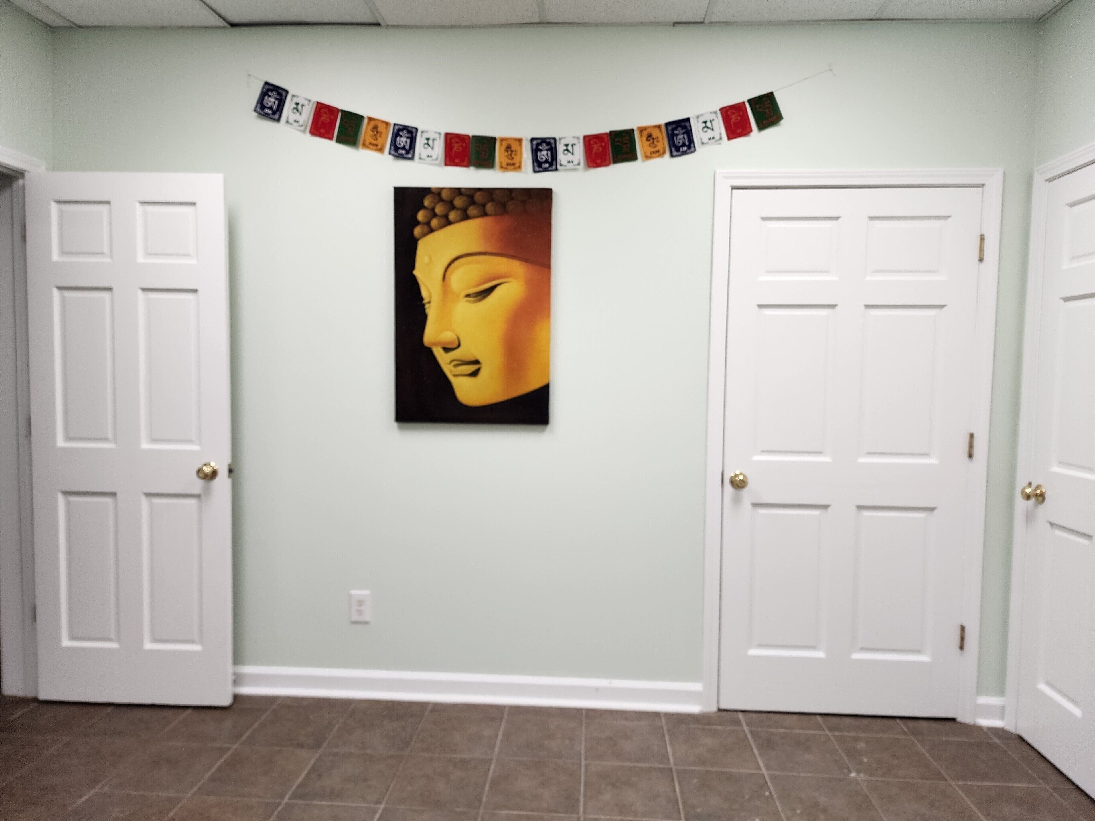 A hallway with two white doors, a wall-mounted painting, and a colorful banner.