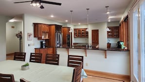 Una cocina moderna con armarios de madera, una isla central y una zona de comedor con mesa y sillas.