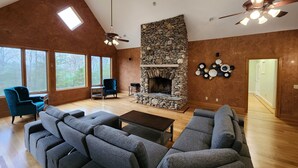 Un salón amplio con chimenea de piedra, ventanas grandes y muebles modernos.