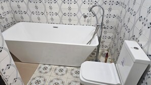 Une salle de bain avec une baignoire sur pieds, des toilettes et un bidet.