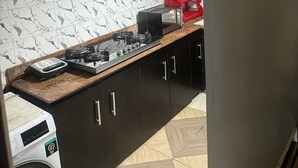 Une cuisine équipée d’une cuisinière à gaz, d’un lave-linge et d’un réfrigérateur.