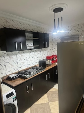 A kitchen with a gas stove, a washing machine, and a refrigerator.