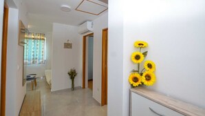 A hallway with a wooden floor, a small desk with a vase of sunflowers, and a door leading to another room. - Holiday Home Eta with Pool (Rovinj)