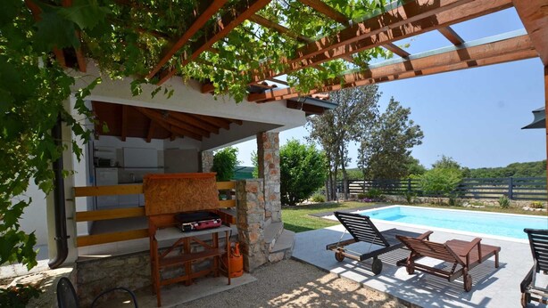 A covered outdoor area with a pool, wooden furniture, and a grill. - Holiday Home Eta with Pool (Rovinj)