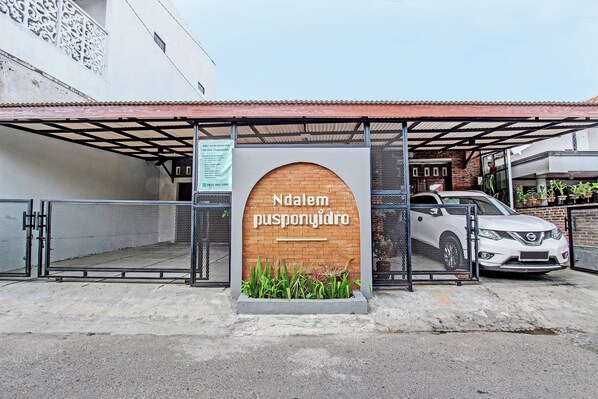 A gated entrance with a sign reading "Ndalem pusponyidro" and a parked car.