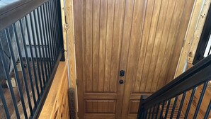 Una scala in legno con ringhiere nere che conduce a una porta con pomello.