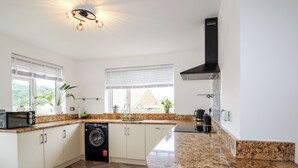 Una cucina moderna con lavatrice integrata, piani di lavoro in granito e un pavimento a spina di pesce.