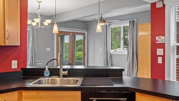 A modern kitchen with a stainless steel sink, wooden cabinets, and pendant lighting.