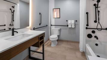 A modern bathroom with a dual sink vanity, a toilet, a shower area with a glass enclosure, and a bathtub.