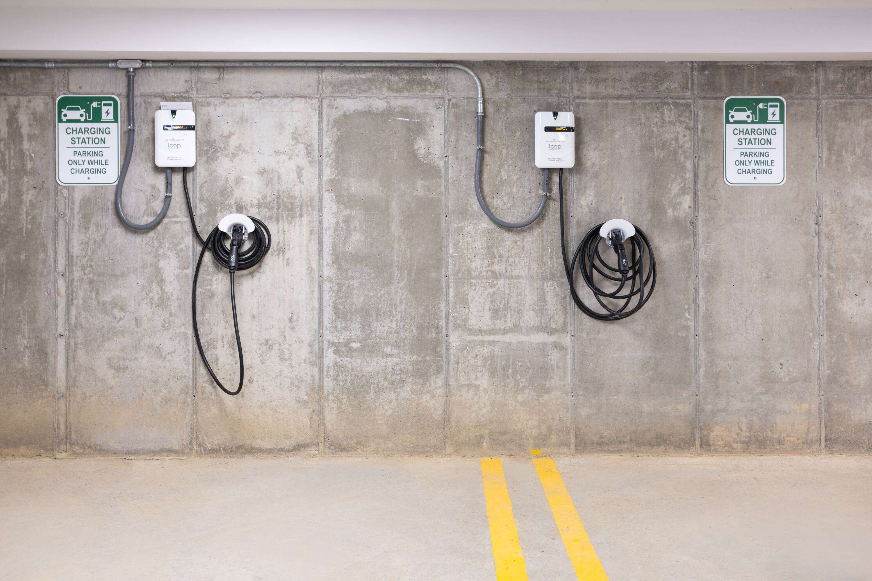 A parking area with two charging stations, each marked with a sign indicating 'charging station' and 'parking only while charging'.