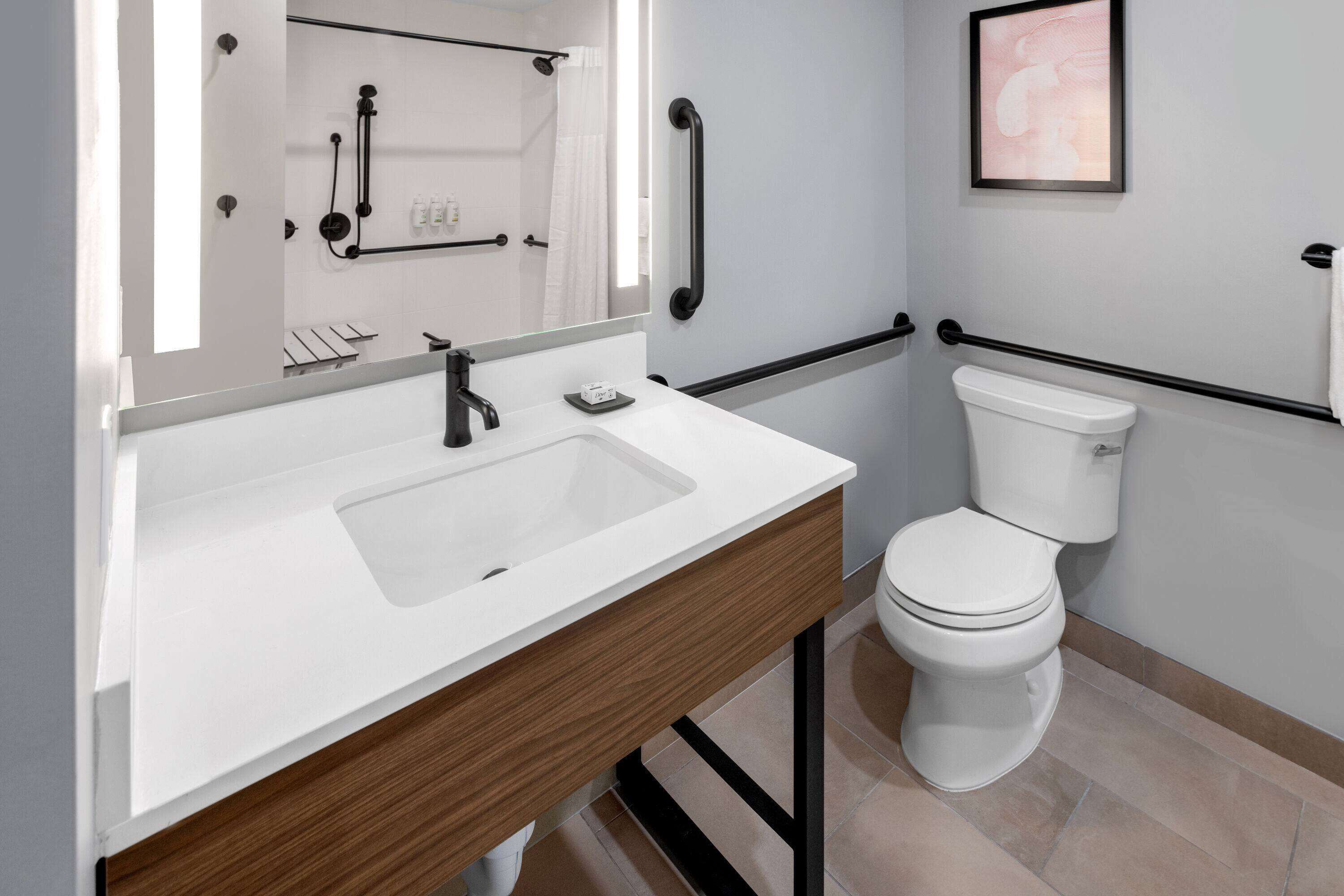 A modern bathroom with a white sink, wooden vanity, and a white toilet.