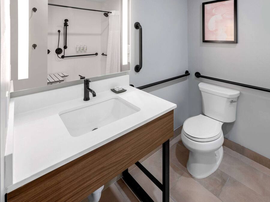 A modern bathroom with a white sink, wooden vanity, and a white toilet.