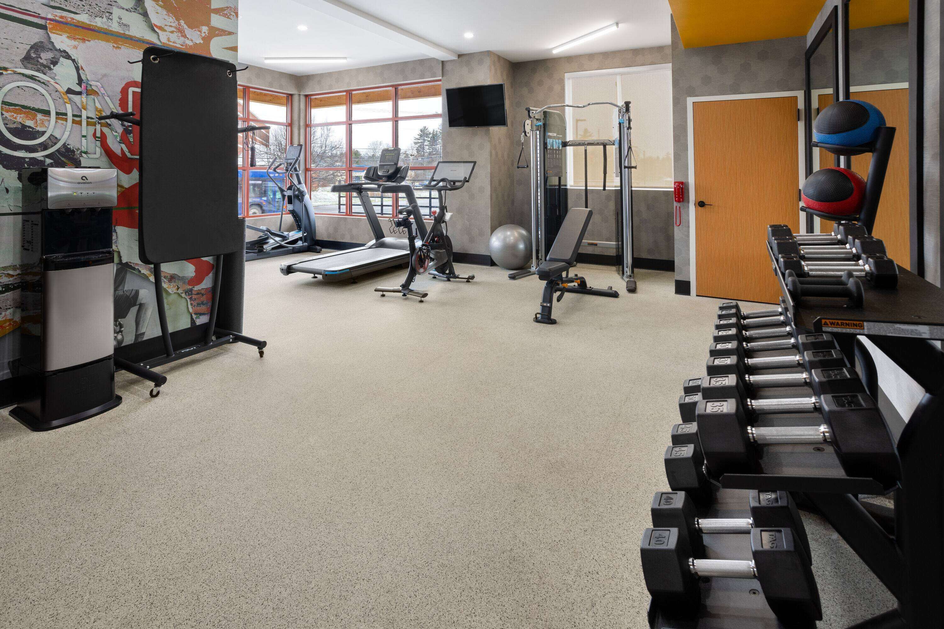 Une salle de sport équipée de tapis de course, d’appareils de musculation et d’un rameur.