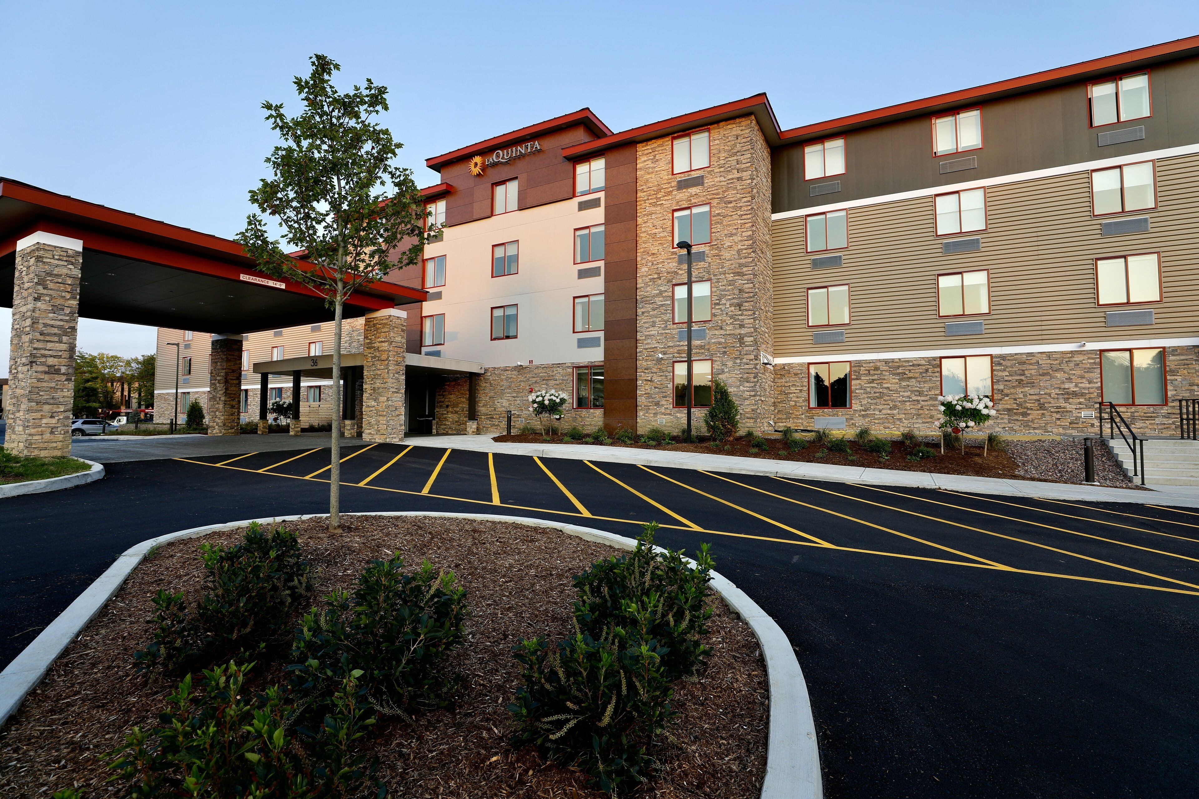A hotel with a covered entrance, parking lot, and landscaped area.