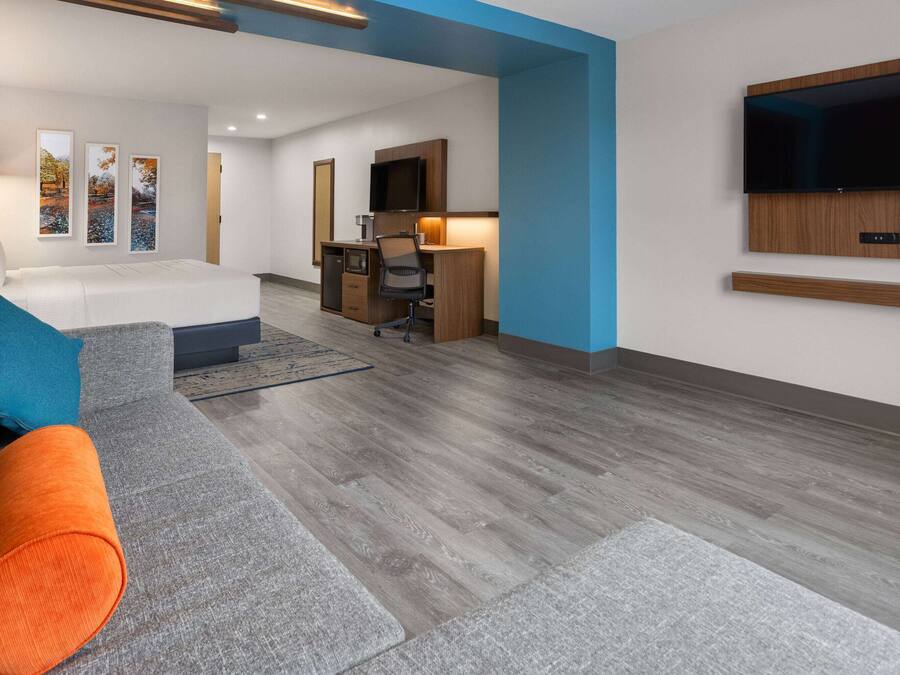 Et moderne hotelværelse med sofa, skrivebord og fjernsyn.
