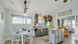 Een moderne keuken met een centraal eiland, een eethoek met een ronde tafel en stoelen, en een zithoek met een bank en salontafel.