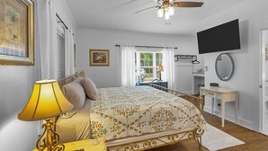 A bedroom with a bed, a ceiling fan, a TV, a dresser, and a window with curtains. - Little Inn on Main 214 West Main Street (Washington)