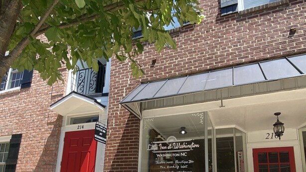 A brick building with a red door and a sign for 'Little Inn at Washington'. - Little Inn on Main 214 West Main Street (Washington)