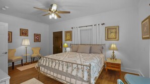 A bedroom with a bed, two bedside tables, a floor lamp, a ceiling fan, and a door. - Little Inn on Main 214 West Main Street (Washington)