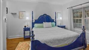 A bedroom with a large bed, two bedside tables, a nightstand, a ceiling fan, a window with blinds, and a door. - Little Inn on Main 214 West Main Street (Washington)