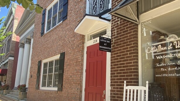 A brick building with a red door and a sign for 'Little Inn at Washington'. - Little Inn on Main 214 West Main Street (Washington)