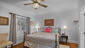 A bedroom with a bed, bedside tables, a chair, a ceiling fan, and a window with blinds. - Little Inn on Main 214 West Main Street (Washington)