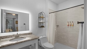 A bathroom with a sink, toilet, and shower. There is a mirror above the sink and a towel rack on the wall. - Little Inn on Main 214 West Main Street (Washington)