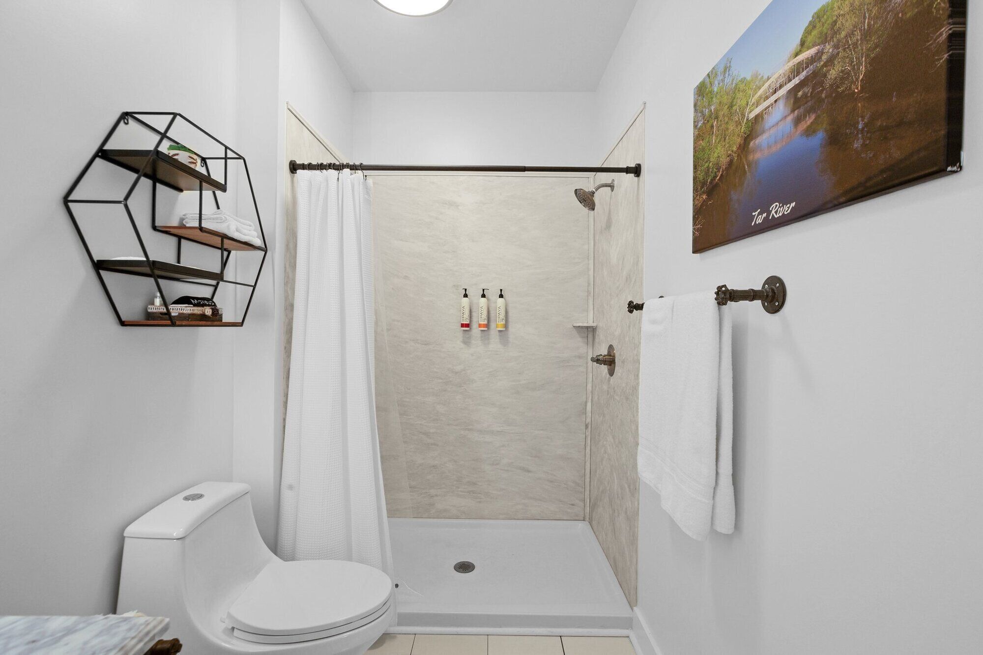 Un baño moderno con ducha, inodoro y un estante hexagonal.