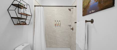 Un baño moderno con ducha, inodoro y un estante hexagonal.