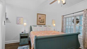 A bedroom with a bed, bedside lamps, a nightstand, a ceiling fan, and a window with shutters. - Little Inn on Main 214 West Main Street (Washington)