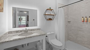 A modern bathroom with a marble sink, a toilet, a shower with a curtain, and a hexagonal shelf with towels.
