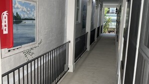 A corridor with a fire extinguisher, an exit sign, and a view of a lake through a window.