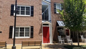 A brick building with a red door, a bench, and a street lamp. - Little Inn on Main 214 West Main Street (Washington)