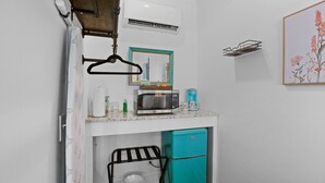 A compact kitchenette with a microwave, a small fridge, a hanging clothes rack, and a framed picture on the wall. - Little Inn on Main 214 West Main Street (Washington)