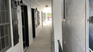 A hallway with doors numbered 201 and 202, a white exterior, and a view of the outside. - Little Inn on Main 214 West Main Street (Washington)