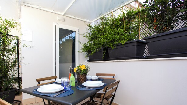 A dining table set for four with chairs, a window, and potted plants. - HOLIDAY HOUSE TERRAZZA MANUELA APARTMENTS 1 (Napoli)