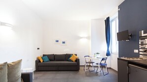 A compact living space with a sofa, a dining table, and a kitchenette. - HOLIDAY HOUSE TERRAZZA MANUELA APARTMENTS 1 (Napoli)