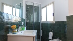 A bathroom with a glass shower enclosure, a sink with a vase of flowers, and a bidet. - HOLIDAY HOUSE TERRAZZA MANUELA APARTMENTS 1 (Napoli)